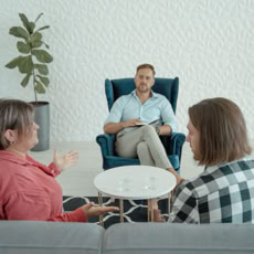 A marriage counselor listens to a couple discussing marital issues in a calm office setting.