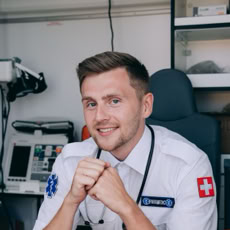 Paramedic in uniform smiling inside an ambulance, showcasing healthcare professionalism.